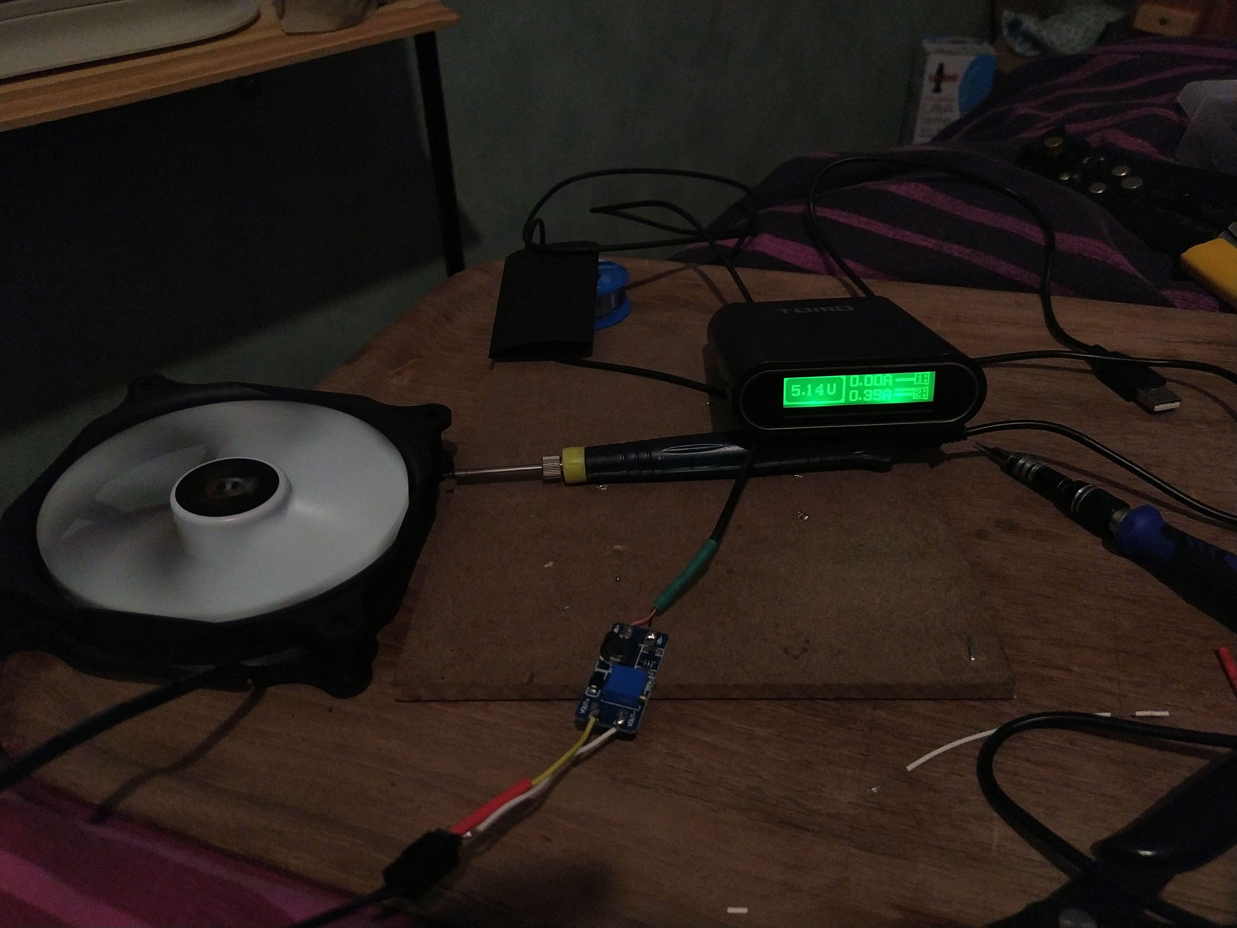 A 120mm fan, small soldering iron, USB power bank, and a circuit board on a small wooden tray, illustrative of how I built my custom 120mm fan